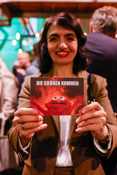 Muhterem Aras hält eine Karte in die Kamera mit dem Slogan "Die Grünen kommen"