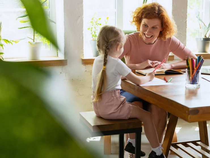 Eine Person sitzt mit einem Kind an einem Tisch und freit sich.